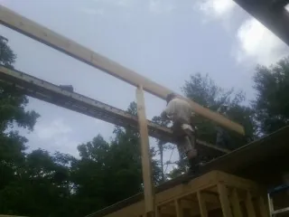 Carpenter setting a ridge beam over a new addition frame — Ice Dam Removal by Roofing Brothers in Rosine