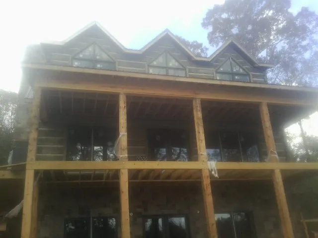 Dormers and porch framing on a large log home under construction — Roof Coating work by our crew in Rosine
