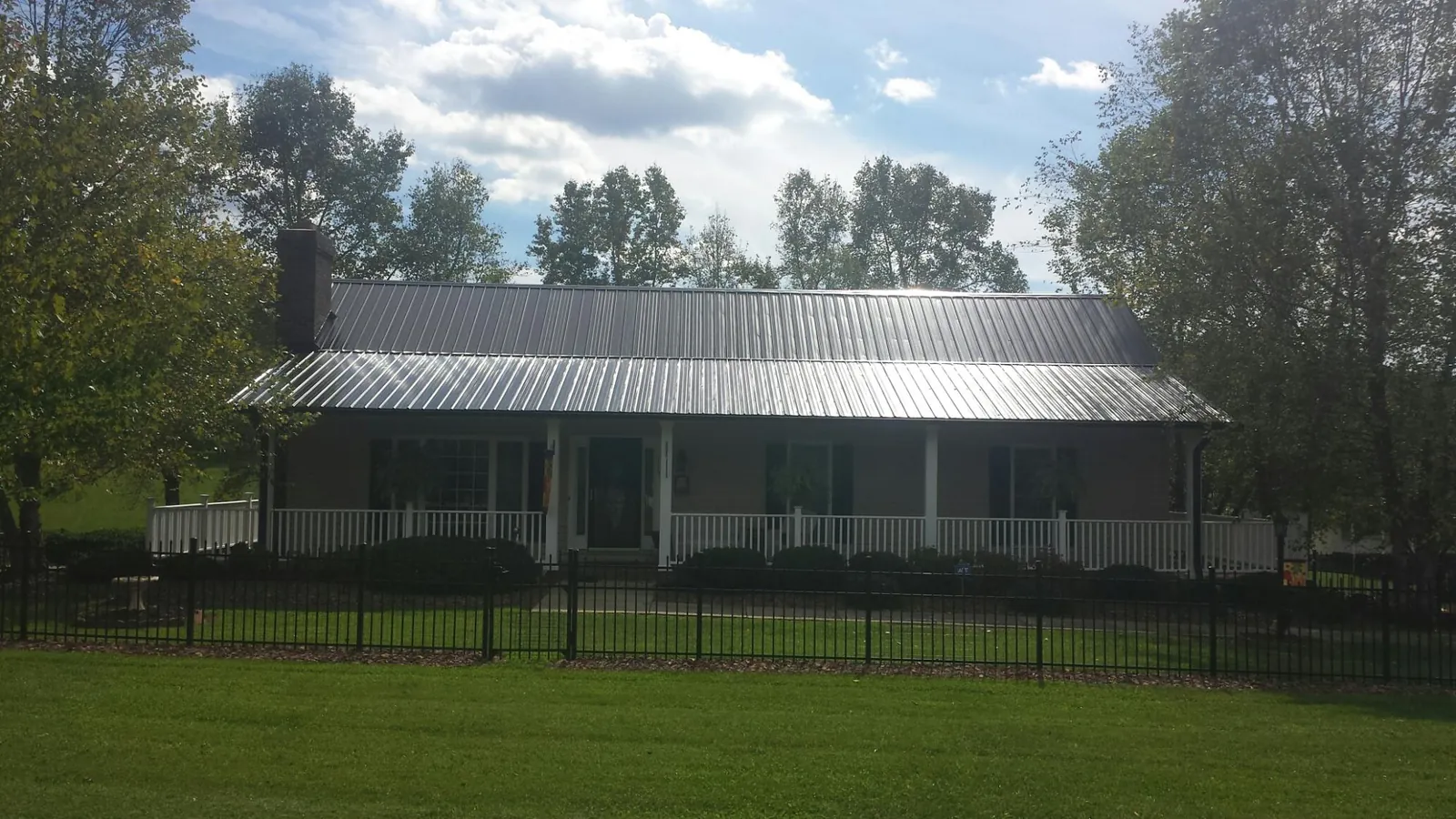 Gray metal roof on a brick ranch with a full width front porch — Gutter Guard Installation work by our crew in Rosine