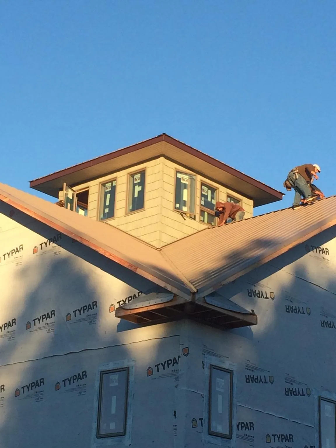 Roofers working around a rooftop cupola on a new metal roof at sunset — Roof Waterproofing in Rosine by Roofing Brothers